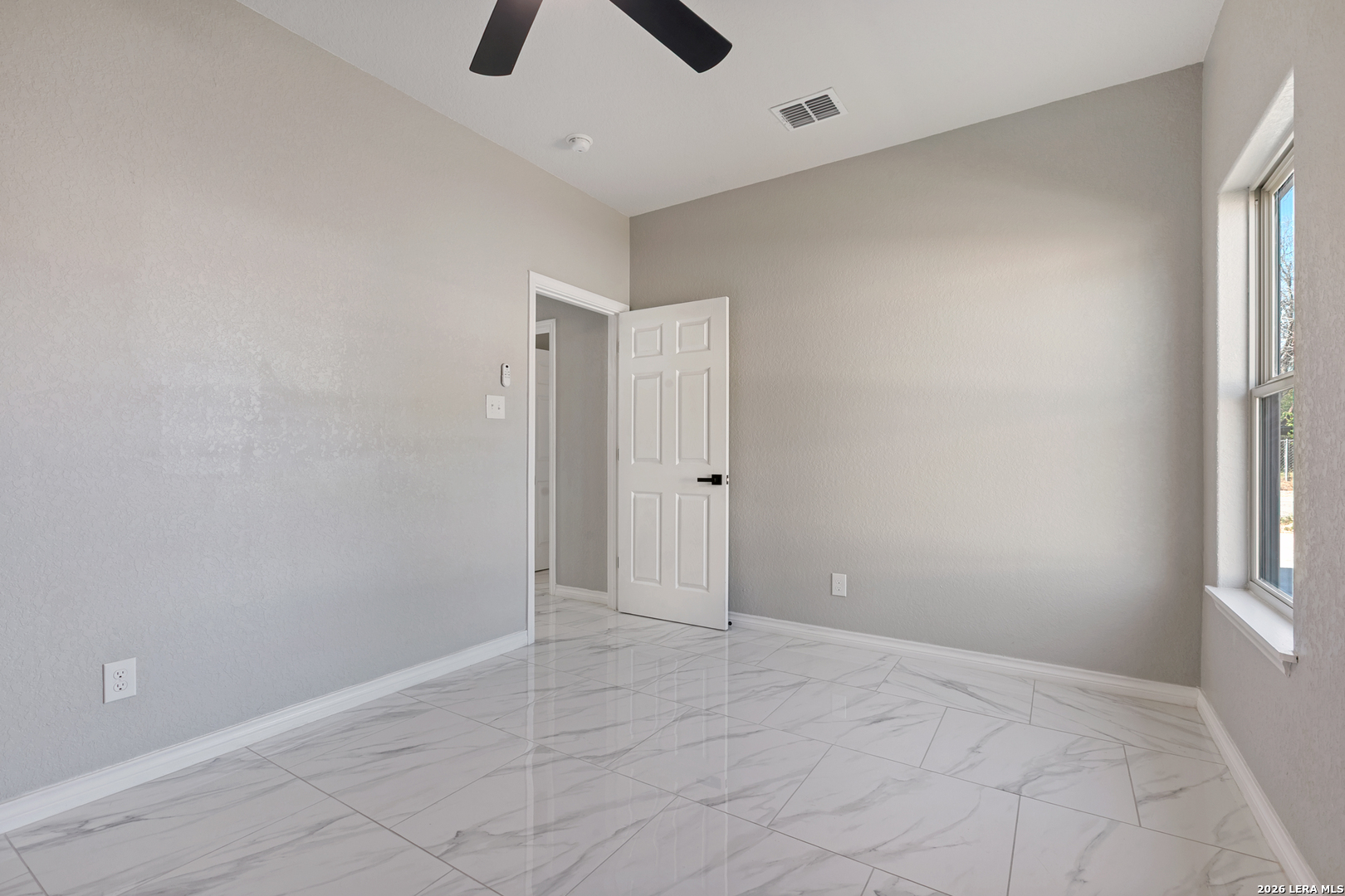 237 Avenue D Poteet, TX 78065 - Photo 25 of 27 an empty room with windows and ceiling fan