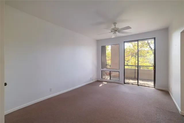 an empty room with windows and ceiling fan