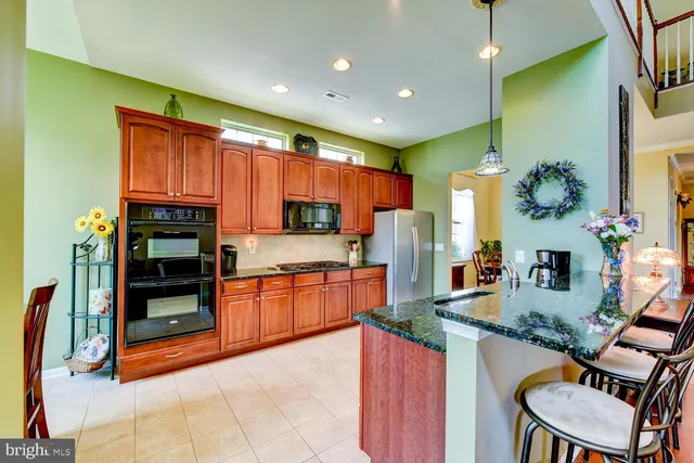 a kitchen with kitchen island granite countertop a stove a sink and a dining table