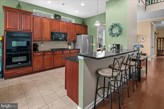 a kitchen with stainless steel appliances granite countertop a stove top oven a sink dishwasher a dining table and chairs with wooden floor