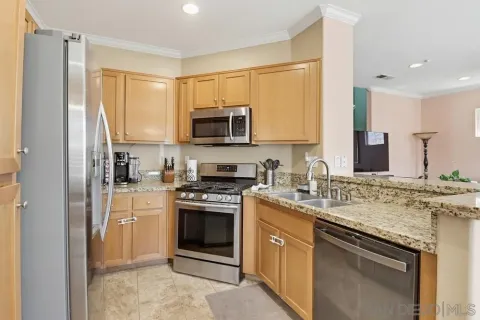 a kitchen with stainless steel appliances granite countertop a stove top oven a sink and a refrigerator