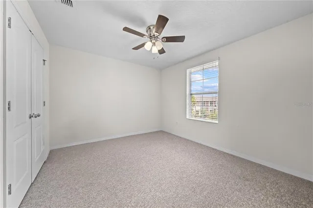 an empty room with ceiling fan and windows