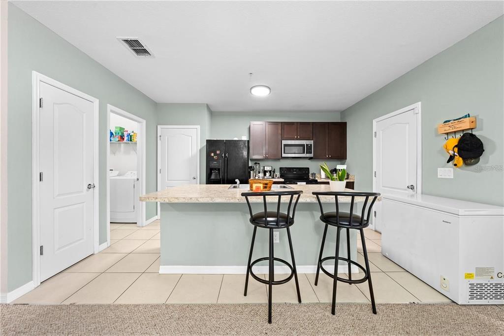 1619 Reflection Cove St. Cloud, FL 34771 - Photo 21 of 54 a kitchen with stainless steel appliances kitchen island granite countertop a refrigerator and a stove top oven