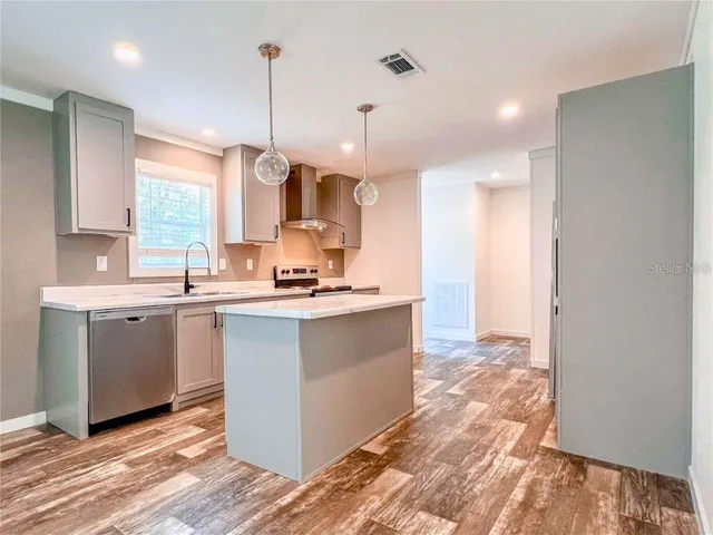 a kitchen with kitchen island granite countertop a sink cabinets and wooden floor