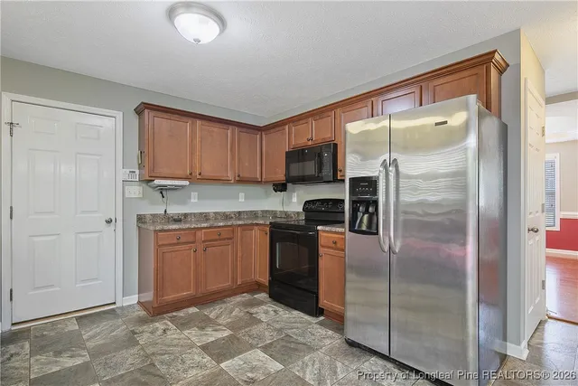 a kitchen with granite countertop a refrigerator and a sink
