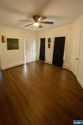 a view of an empty room with window and wooden floor