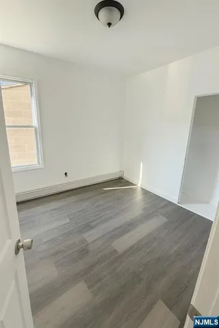 an empty room with wooden floor and window