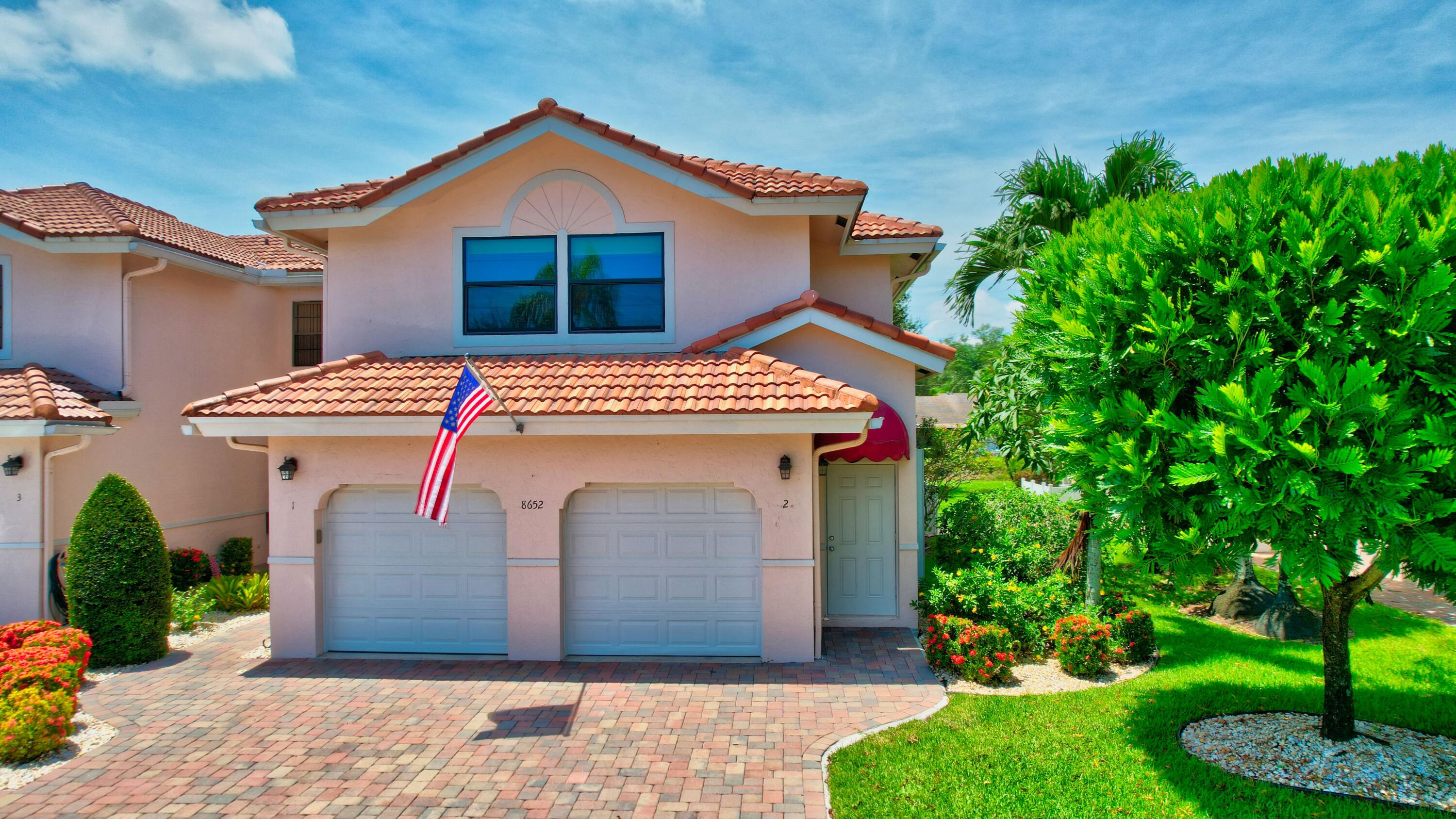8652 Vía Reale, Unit 2 Boca Raton, FL 33496 - Photo 34 of 58 a front view of a house with a yard and garage