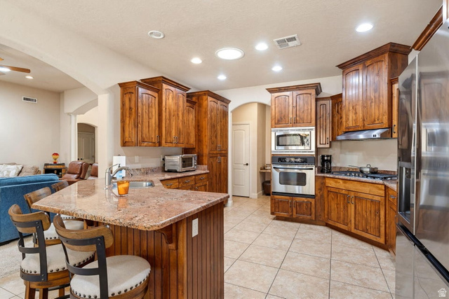 1609 East 10 S Street St. George, UT 84790 - Photo 19 of 68 Kitchen featuring rich wood cabinetry, granite countertops, stainless steel appliances, a built-in oven and microwave, and tile flooring