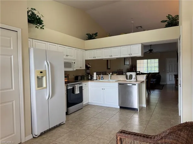 a kitchen with a refrigerator and white cabinets