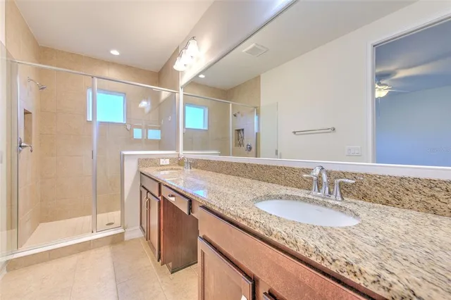 a bathroom with a granite countertop sink a mirror and a shower