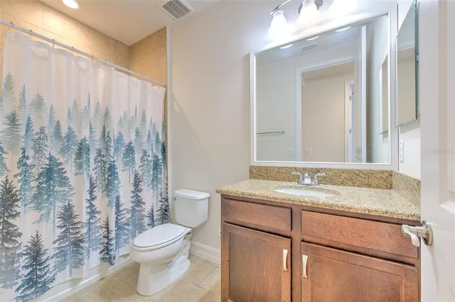 a bathroom with a granite countertop sink toilet and mirror