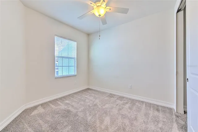 an empty room with a window and a chandelier fan