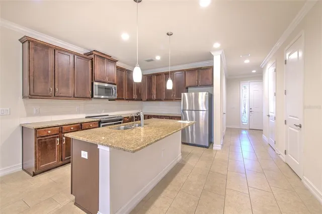 a large kitchen with a large counter top stainless steel appliances and cabinets