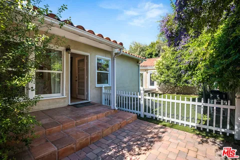 a view of a house with a small yard and wooden fence