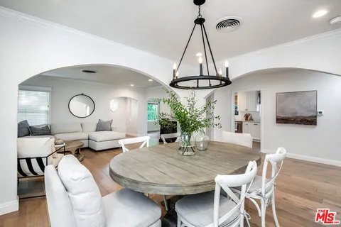 a dining room with wooden floor a chandelier a glass table and chairs