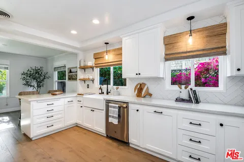 a kitchen with white cabinets and sink