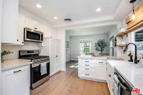 a kitchen with white cabinets and appliances