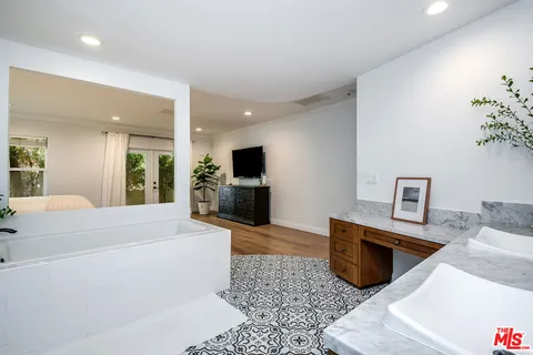 a large white kitchen with stainless steel appliances kitchen island granite countertop a sink and a stove top oven with wooden floor