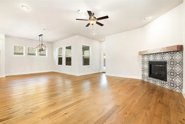 an empty room with wooden floor fireplace and windows