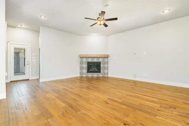 an empty room with wooden floor ceiling fan and windows