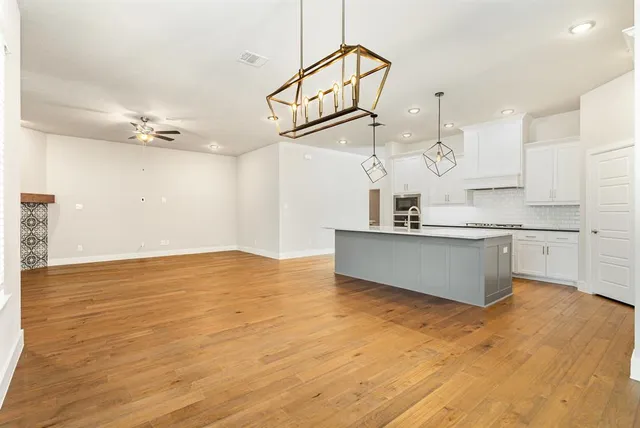 a view of a kitchen with kitchen island a sink stainless steel appliances and cabinets