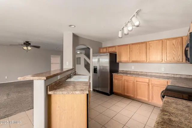 a kitchen with stainless steel appliances granite countertop a refrigerator a sink dishwasher a stove with wooden cabinets and floor