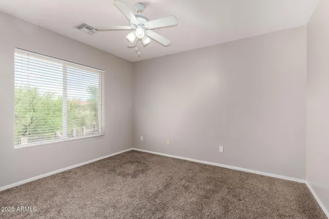 an empty room with closet and a chandelier fan