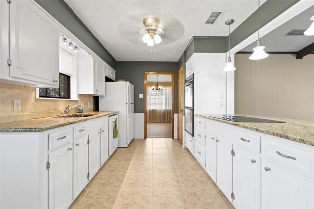 a large white kitchen with granite countertop a large window and white stainless steel appliances