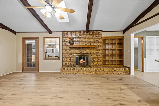 a view of a livingroom with wooden floor a ceiling fan and a fireplace