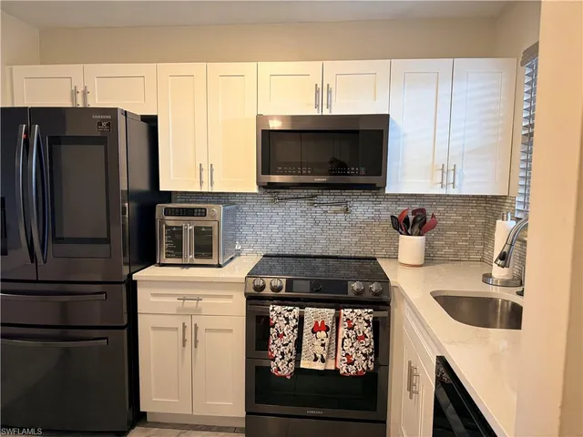 a kitchen with granite countertop a refrigerator stove and microwave