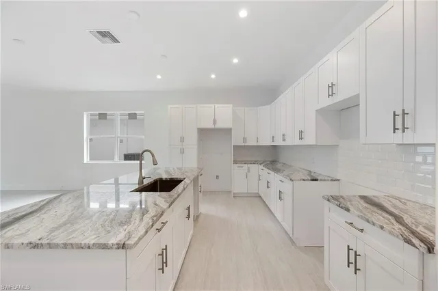 a kitchen with granite countertop a sink a stove a microwave and island