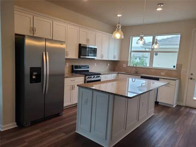 a kitchen that has a lot of cabinets and wooden floor