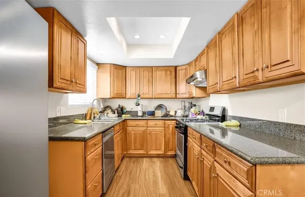a kitchen with stainless steel appliances granite countertop a sink a stove cabinets counter space and a window