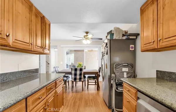 a kitchen with stainless steel appliances granite countertop a refrigerator a sink dishwasher a stove and white countertops with wooden floor