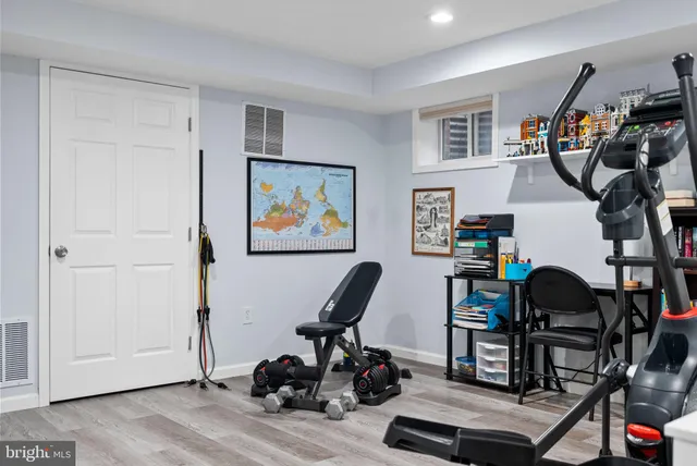 a house that is sitting in the grass with large trees and plants