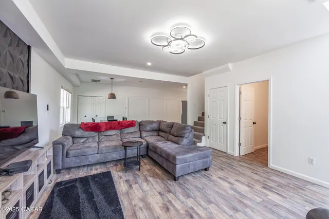 a kitchen with stainless steel appliances granite countertop a refrigerator a sink dishwasher a stove and white countertops with wooden floor