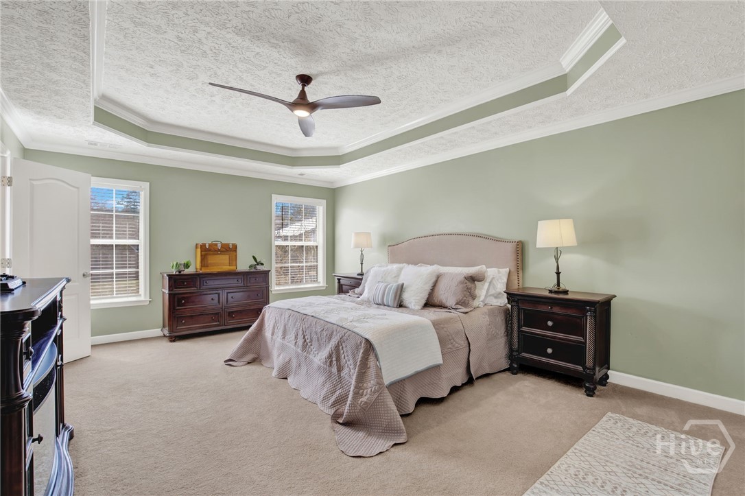 253 Scuffletown Road Guyton, GA 31312 - Photo 16 of 37 Spacious primary suite featuring tray ceilings, neutral tones, and abundant natural light.