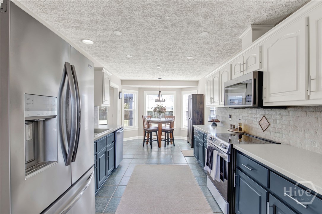 253 Scuffletown Road Guyton, GA 31312 - Photo 20 of 37 Galley-style kitchen featuring stainless appliances, ample cabinetry, and a sunny breakfast nook overlooking the backyard.