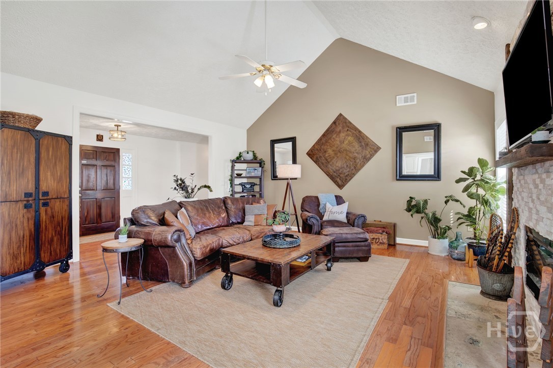 253 Scuffletown Road Guyton, GA 31312 - Photo 7 of 37 Spacious living room with vaulted ceilings, hardwood floors, and a cozy fireplace creating an ideal gathering space.