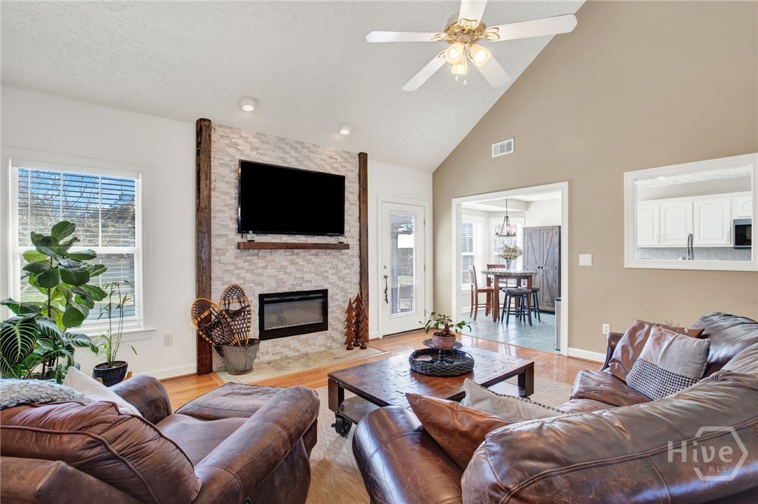 253 Scuffletown Road Guyton, GA 31312 - Photo 9 of 37 Bright living room showcasing a vaulted ceiling, statement fireplace, and seamless flow into the dining area.