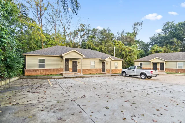 a wooden house with large trees and wooden fence
