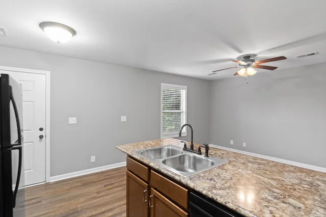 a kitchen with a sink granite counter tops and a ceiling fan