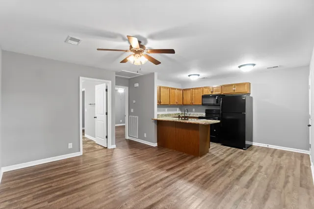 a large kitchen with a refrigerator and a wooden floor