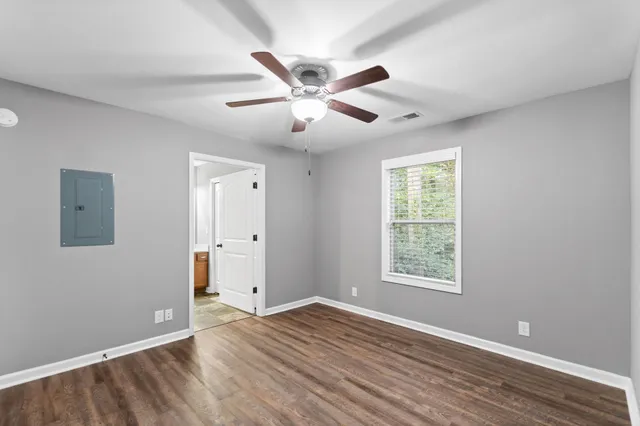 a view of an empty room with wooden floor and a window