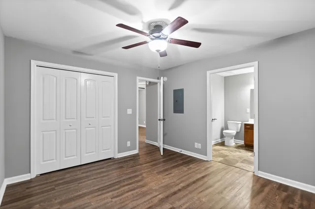 a view of an empty room with wooden floor and a ceiling fan