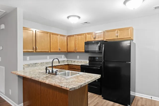 a kitchen with a sink a refrigerator a stove a kitchen island and cabinets