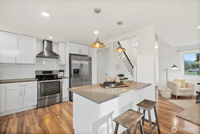a kitchen with stainless steel appliances kitchen island granite countertop a sink a stove and chairs