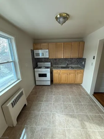 a view of kitchen with granite countertop cabinets and window