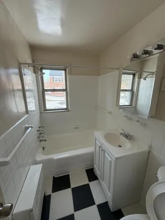 a bathroom with a sink a toilet a shower a window and a mirror